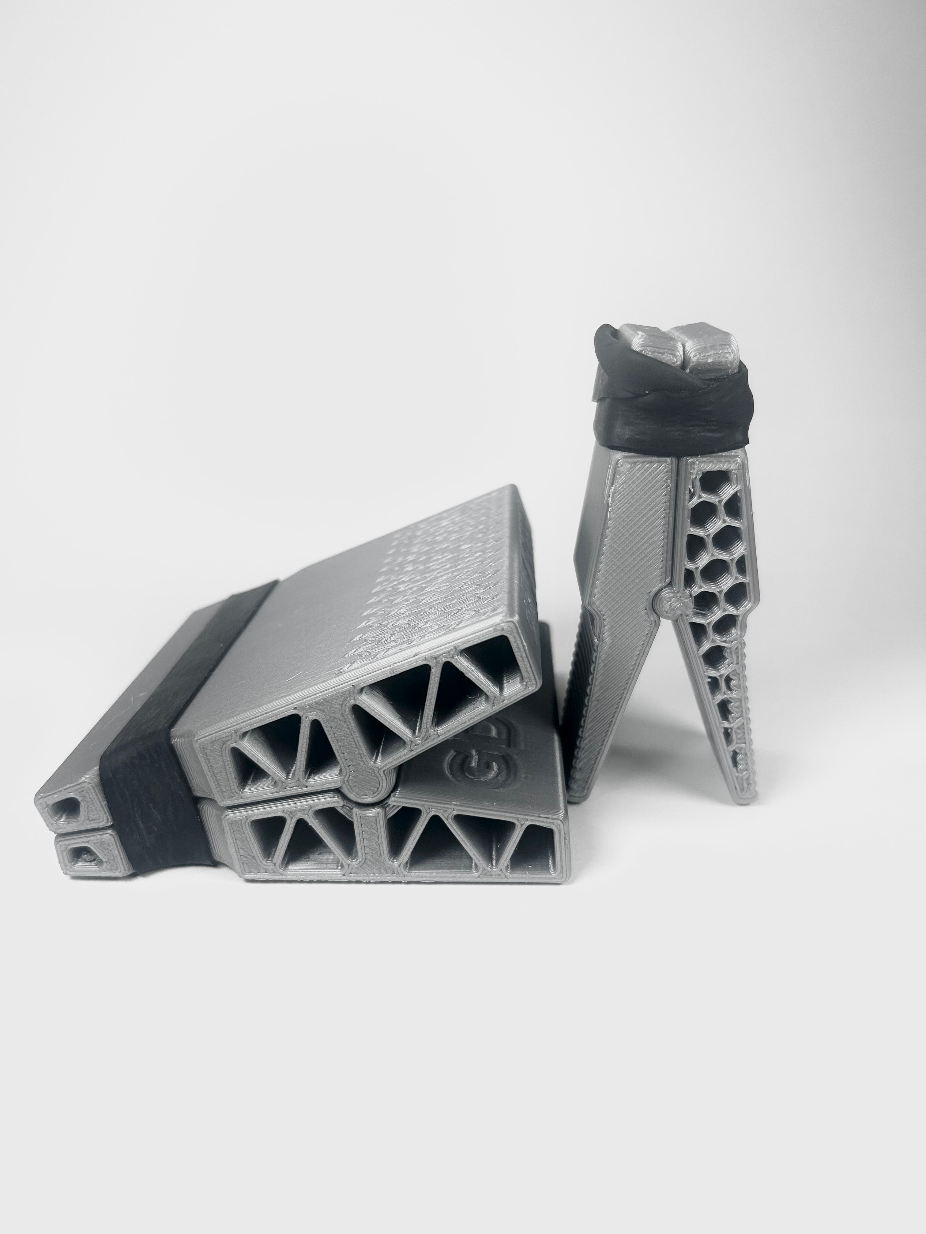 A pair of gray 3D-printed climbing holds with black textured grips, displayed on a clean light gray background.
