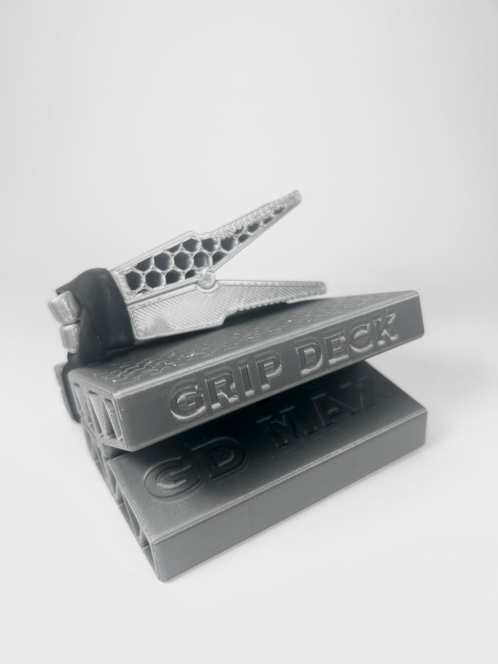 A 3D-printed grip deck tool for 3D printed pens, shown open on top of two closed gray practice grips against a light gray background.